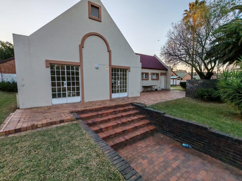 Rear exterior view of the property featuring a brick paved patio, tiered brick steps, and a landscaped garden area.