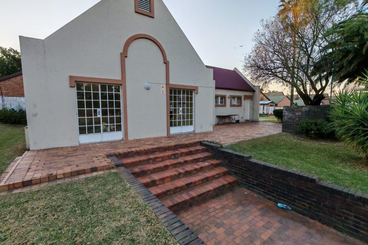 Rear exterior view of the property featuring a brick paved patio, tiered brick steps, and a landscaped garden area.