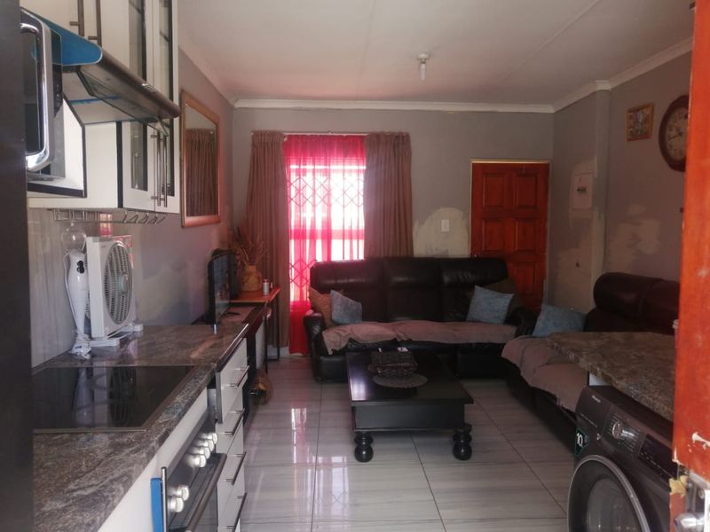 Open-plan living area featuring a compact kitchen with granite countertops and tiled flooring, requiring minor cosmetic updates to wall finishes.