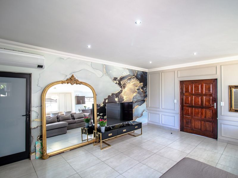 A well-maintained living room featuring decorative wainscoting, tiled flooring, recessed lighting, and a statement feature wall with a modern air conditioning unit.