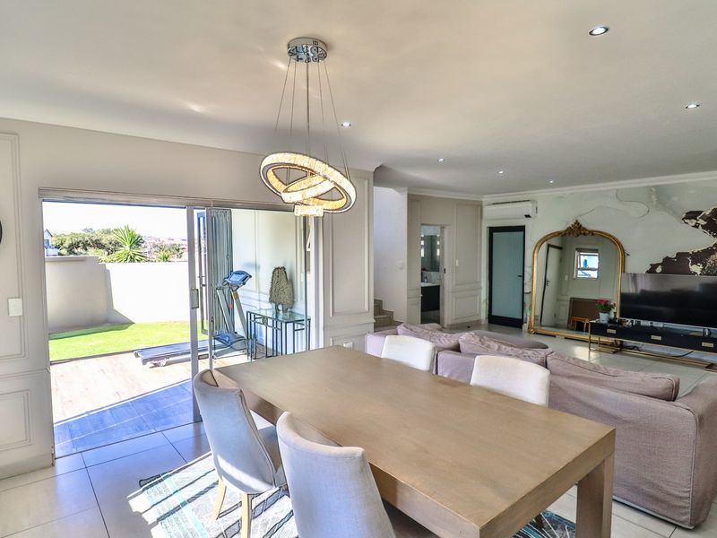 Spacious open-plan living and dining area featuring modern tiled floors, decorative wall molding, recessed lighting, and large sliding doors leading to an outdoor patio.