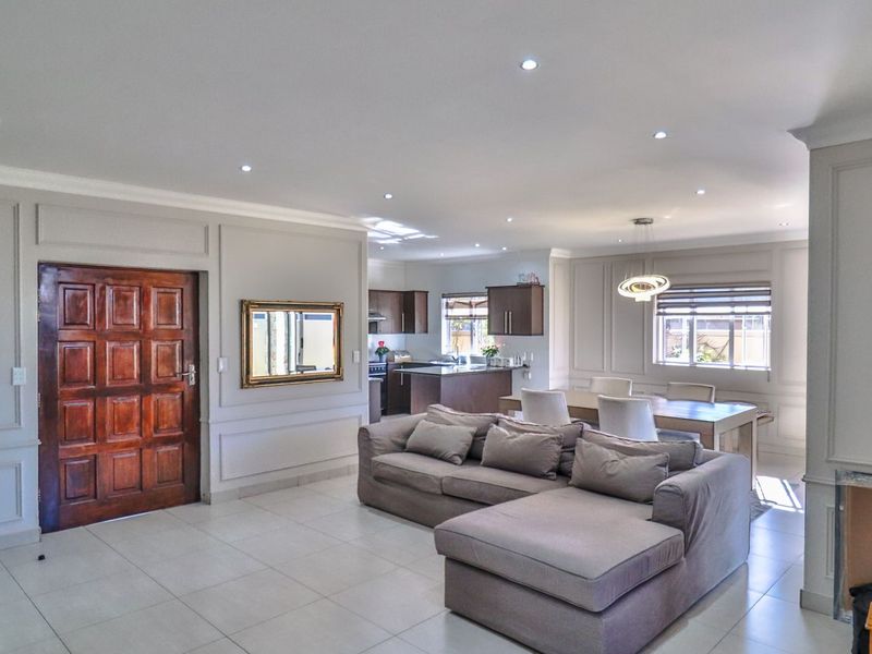 Spacious open-plan living and dining area featuring elegant wainscoting, tiled flooring, recessed lighting, and a modern kitchen with integrated cabinetry.