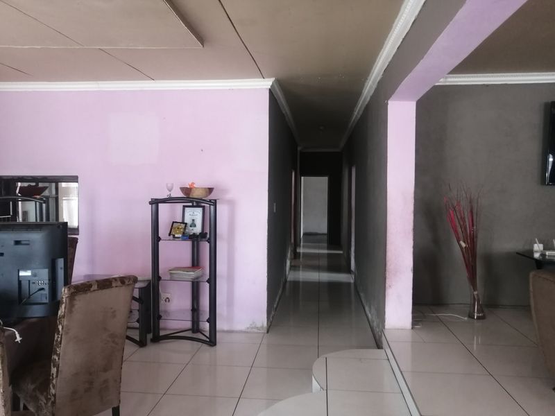A hallway connecting living areas, featuring tiled flooring and coved ceilings, currently showing signs of wear and requiring cosmetic updates to the wall finishes.