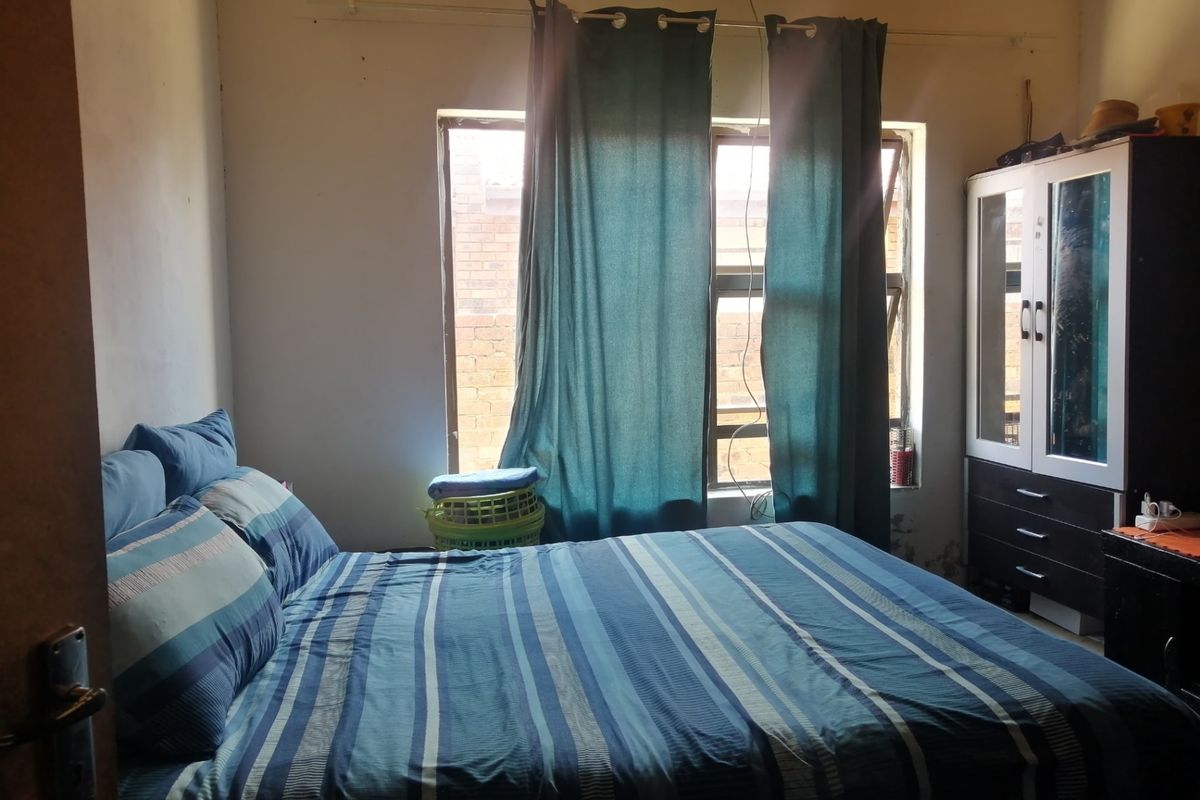 A bedroom featuring a window with natural light, requiring cosmetic updates to the wall finishes and general maintenance.
