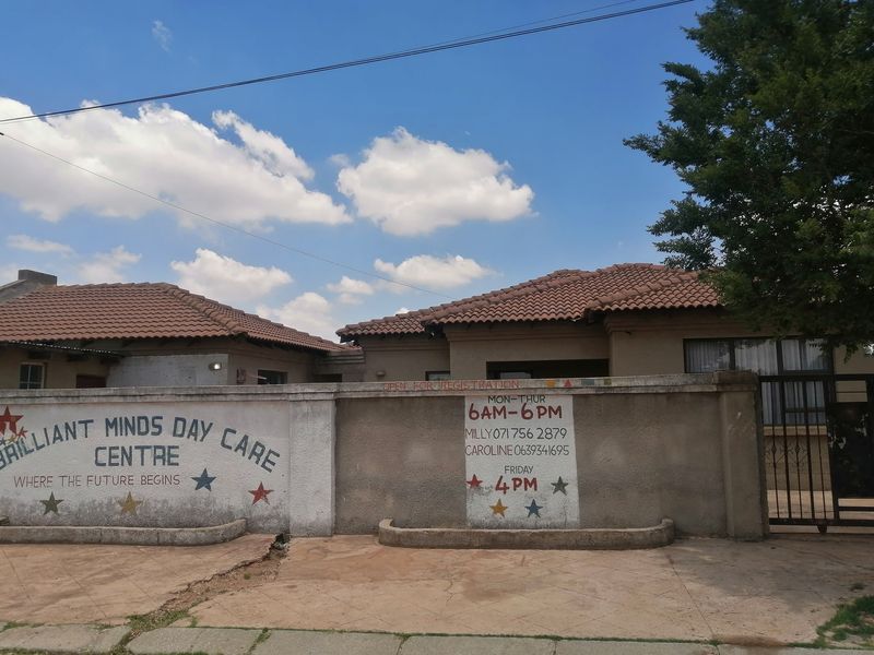 Front exterior view of a residential property featuring a tiled roof, boundary wall, and metal gate, currently utilized as a day care centre.
