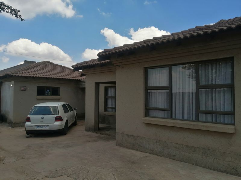 Front exterior view of a single-story house featuring a tiled roof, concrete driveway, and aluminium window frames.