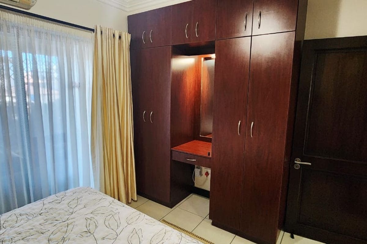 Bedroom featuring dark wood built-in cupboards with an integrated vanity station, tiled flooring, and access to a balcony through a sliding door.