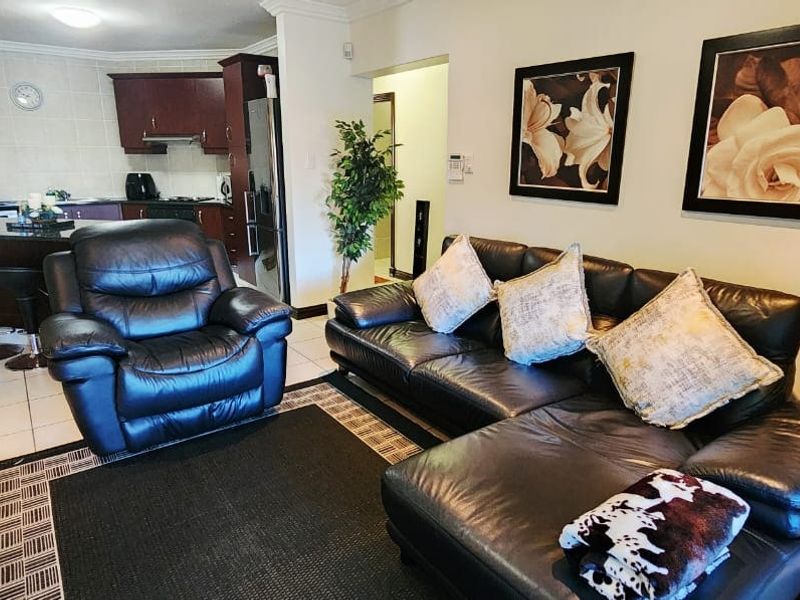 Open-plan living area featuring a kitchen with dark cabinetry, granite countertops, and tiled flooring, seamlessly flowing into the lounge space.