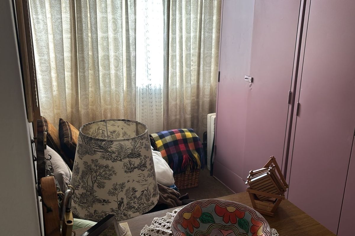 A bedroom featuring a built-in wardrobe and window with curtains, offering a functional space with potential for modernization.