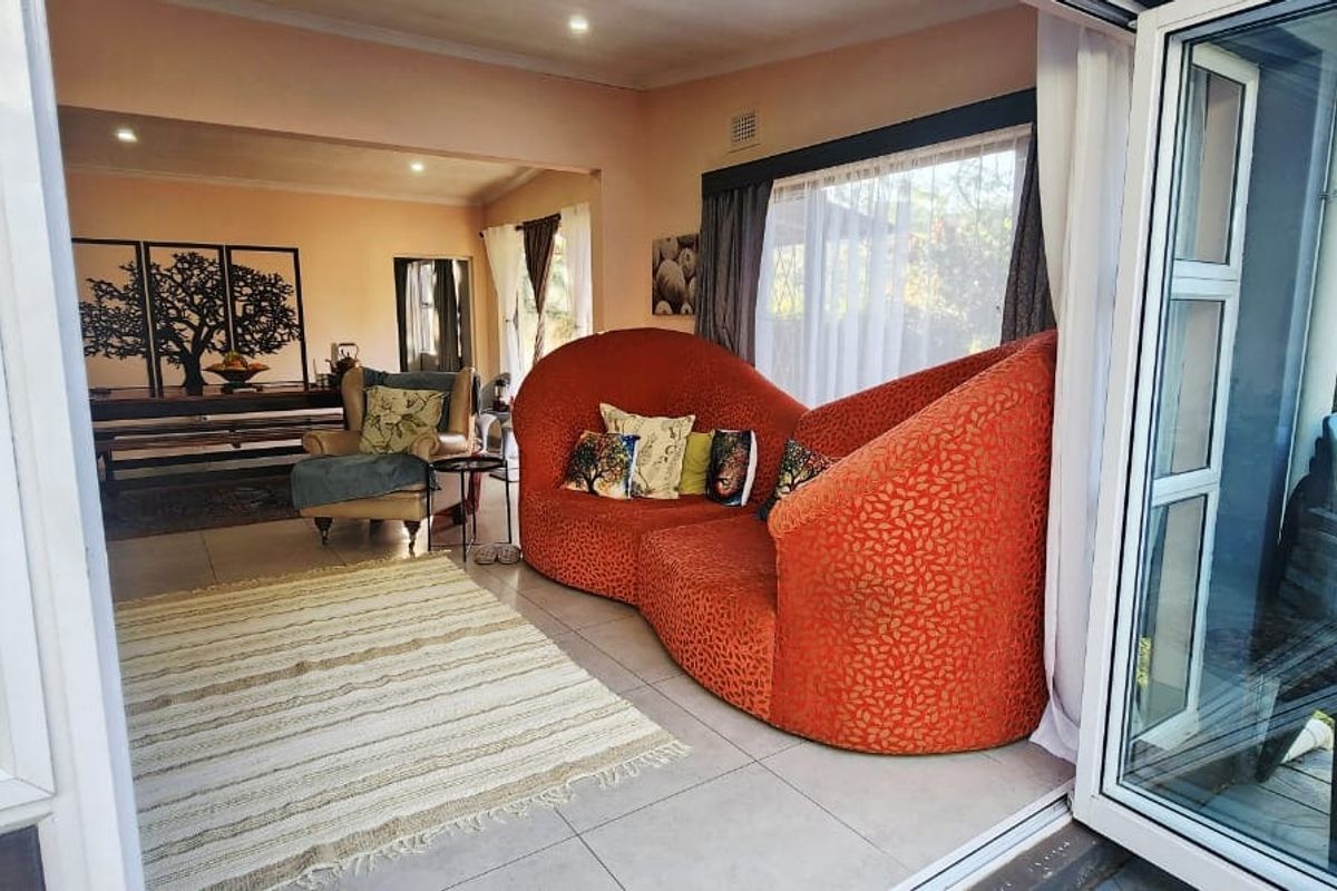 A bright living room featuring large aluminium folding doors that open to an outdoor area, with tiled flooring and recessed lighting throughout.
