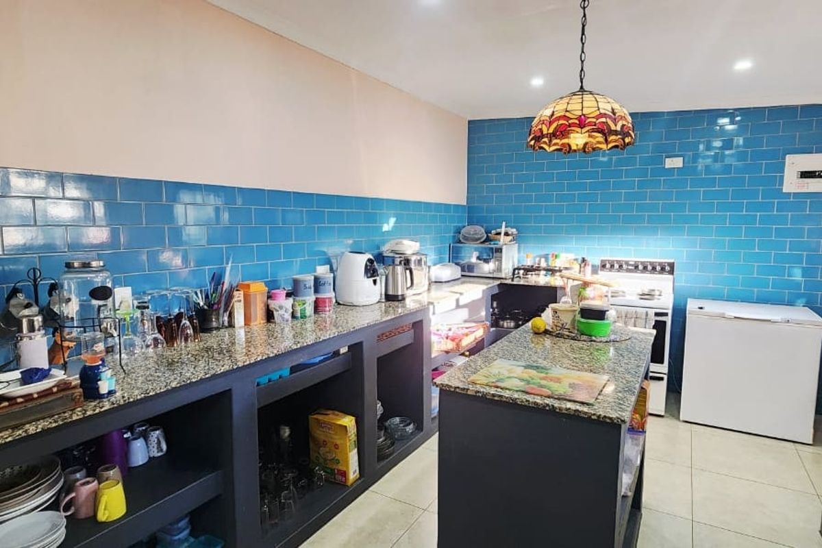A functional kitchen featuring blue subway tile backsplashes, granite countertops, a central island, and ample built-in storage cabinetry.
