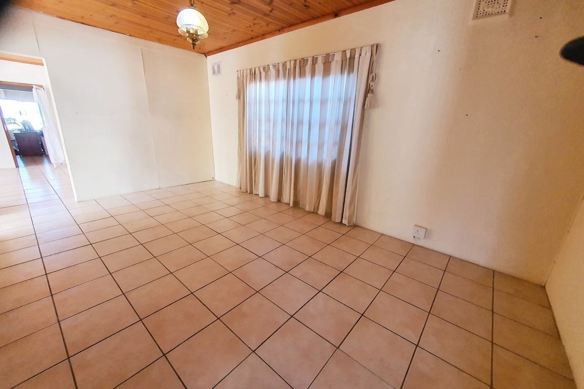 An empty living room featuring tiled flooring and a timber tongue and groove ceiling, offering a blank canvas for interior design.