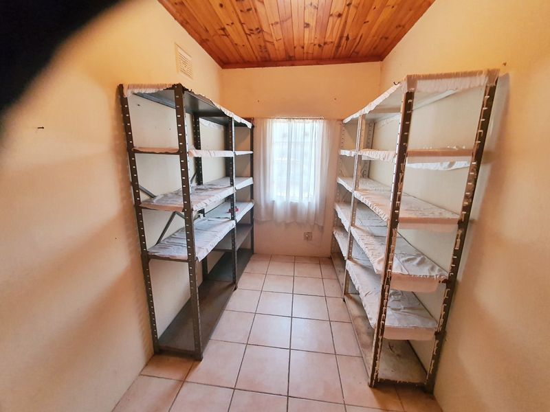 A functional utility or storage room featuring tiled flooring and a timber ceiling, providing ample space for organization and household storage.