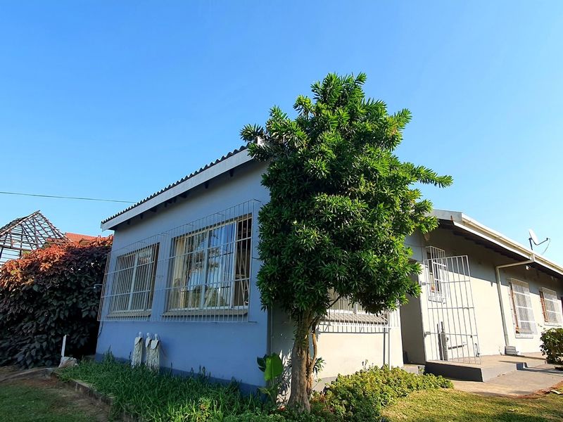Front exterior view of a single-story house featuring security bars on windows and a tiled roof, set within a residential garden area.