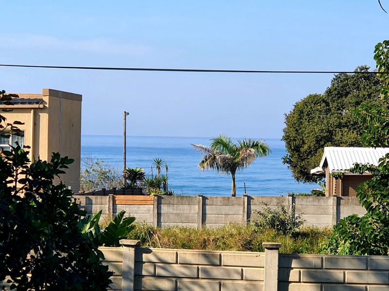 A clear view of the ocean from the property, featuring a precast concrete boundary wall and surrounding greenery.