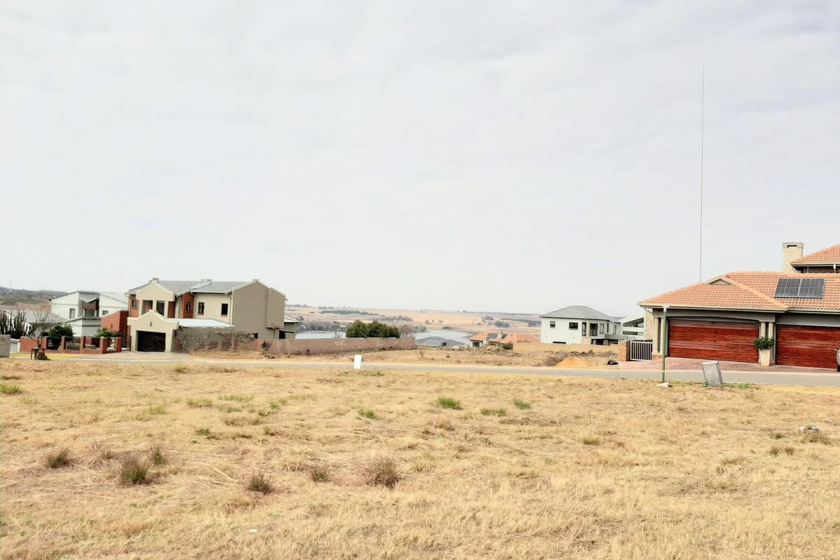 A view of a vacant residential plot in a developed estate, showcasing the surrounding neighborhood and landscape.