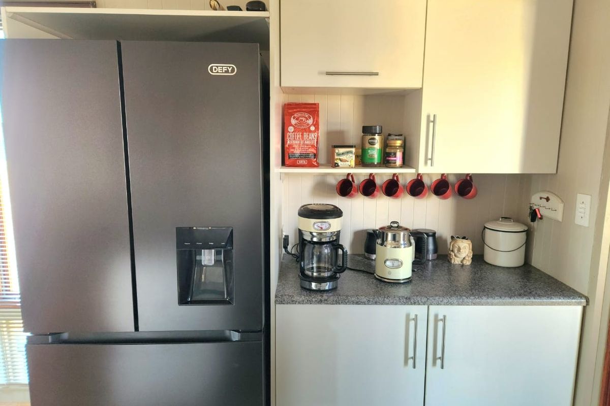 A functional kitchen corner featuring built-in cabinetry, a laminate countertop, and a modern double-door refrigerator.