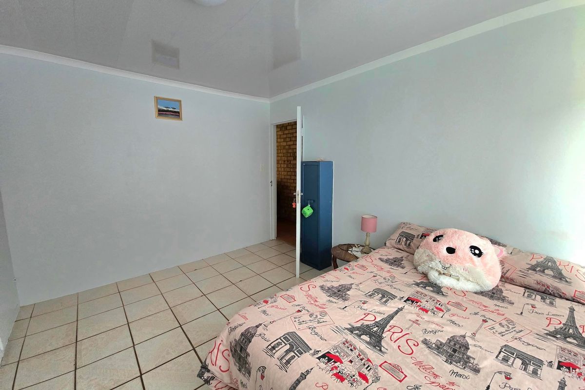 A bedroom featuring neutral wall finishes, ceramic floor tiles, and a coved ceiling, providing a functional and clean living space.