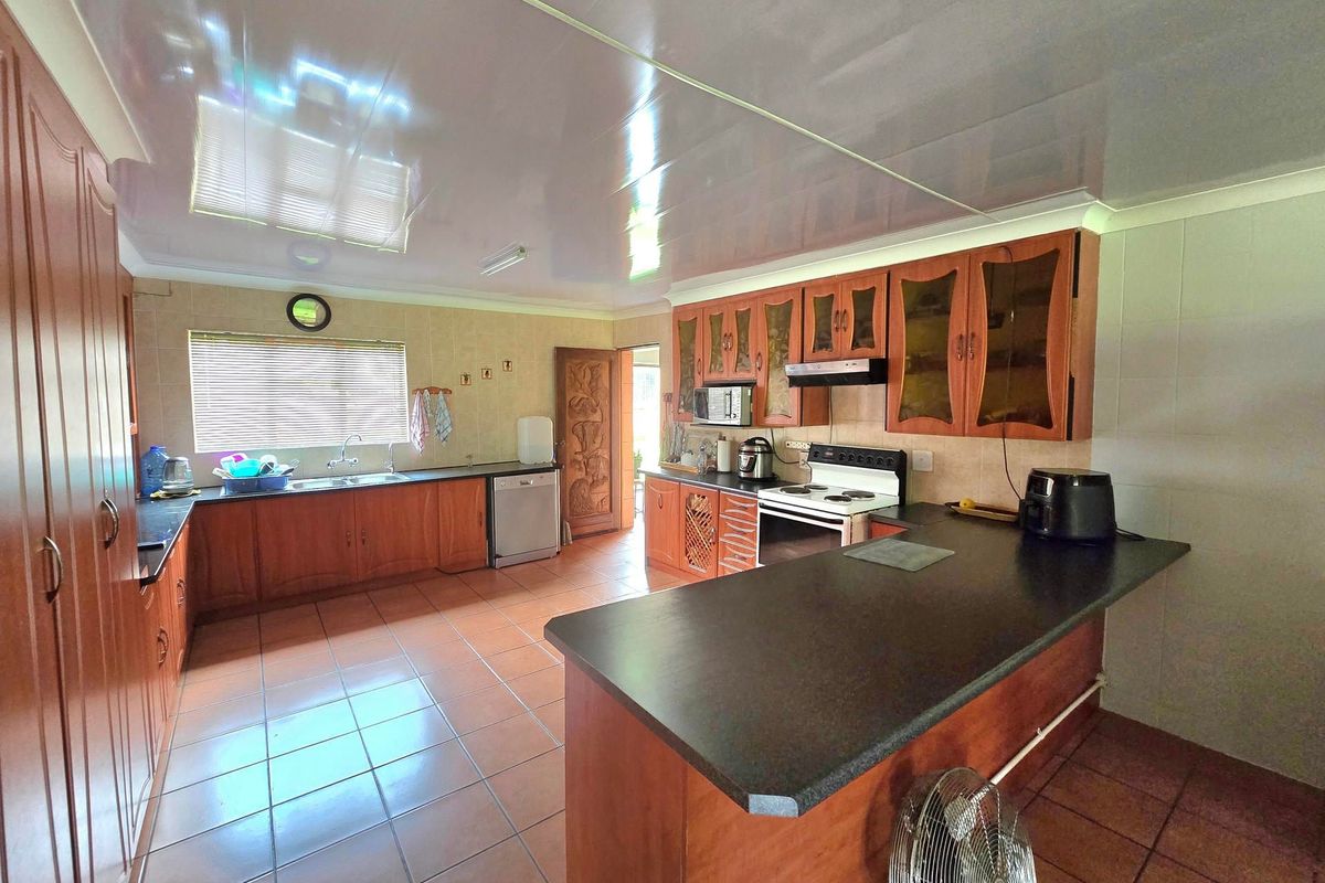 Spacious kitchen featuring extensive wooden cabinetry, laminate countertops, a double basin sink, and a functional layout with a breakfast bar area.