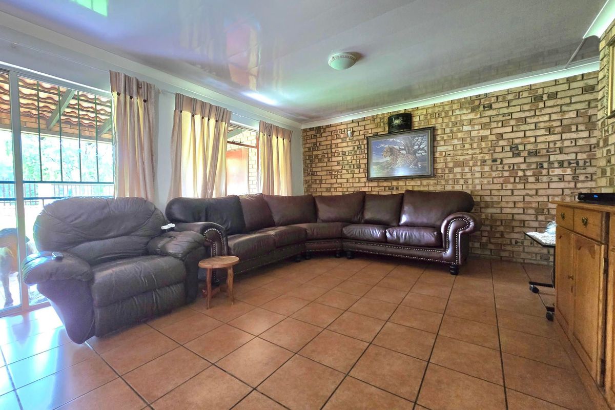 Spacious living room featuring an exposed brick feature wall, ceramic floor tiles, and a sliding glass door providing access to the outdoor area.