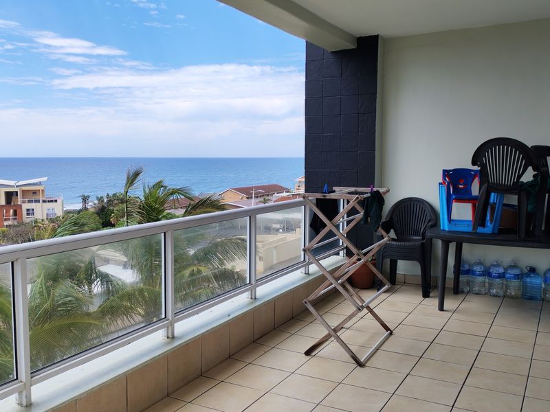 Spacious covered balcony featuring a glass balustrade and tiled flooring, offering expansive ocean views.