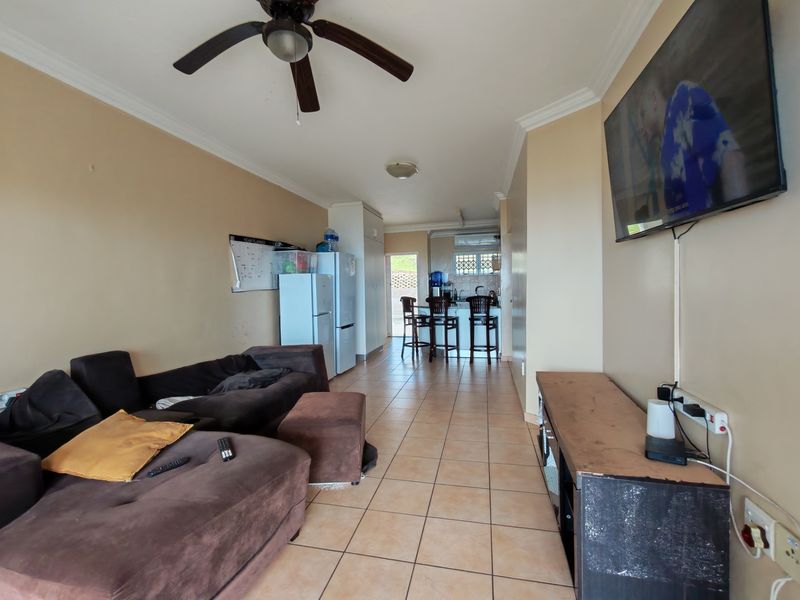 Open-plan living and kitchen area featuring tiled flooring, crown molding, and a breakfast bar, offering a functional layout for daily living.