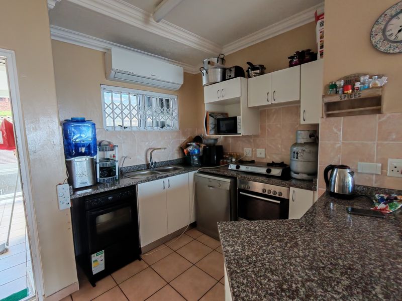 Functional kitchen featuring granite countertops, built-in oven, hob, and ample cabinetry, with direct access to an outdoor area.