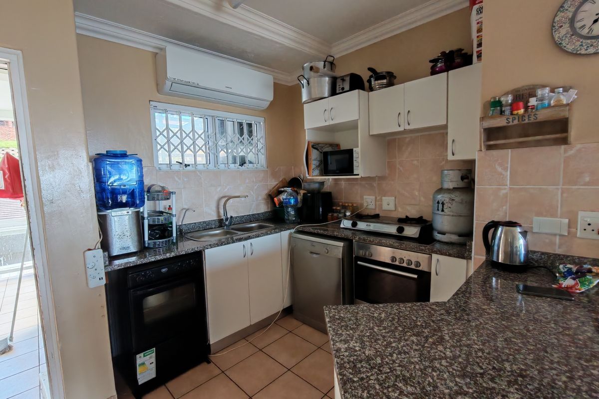 Functional kitchen featuring granite countertops, built-in oven, hob, and ample cabinetry, with direct access to an outdoor area.