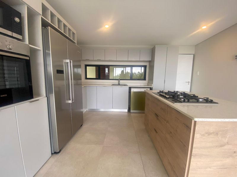 Modern kitchen featuring a central island with a gas hob, built-in oven, microwave, and sleek cabinetry with stone countertops.