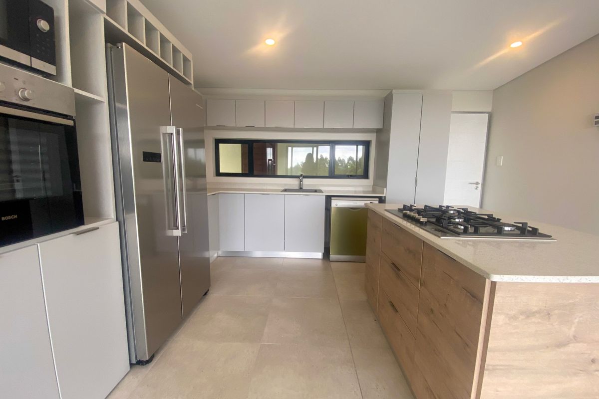 Modern kitchen featuring a central island with a gas hob, built-in oven, microwave, and sleek cabinetry with stone countertops.