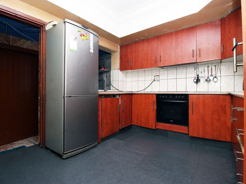A functional kitchen featuring wood-tone cabinetry, tiled backsplash, and built-in oven, offering potential for modernization and aesthetic updates.