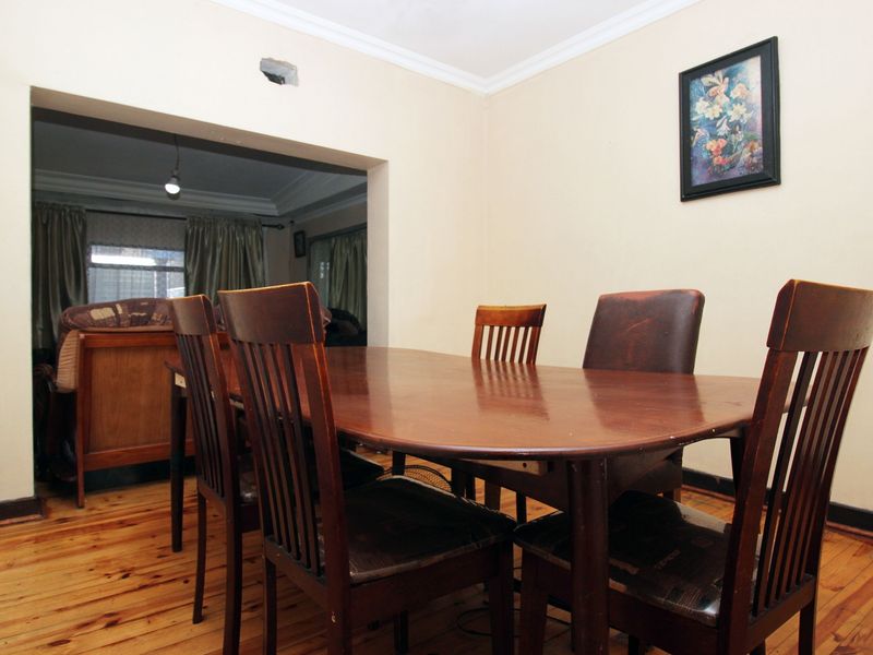 Dining room featuring timber flooring and cove cornice, with an open transition to the adjacent living area.