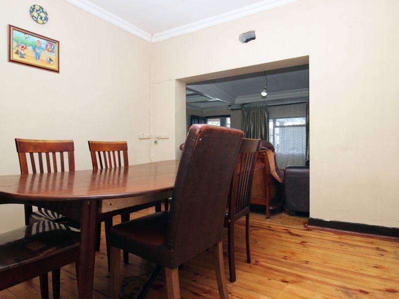 Dining room featuring timber flooring and cove cornicing, with an open transition to the adjacent living area.