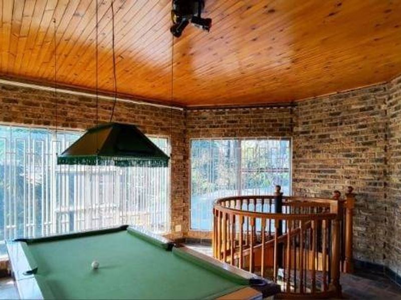 Spacious living area featuring exposed brick walls, a warm timber ceiling, and a spiral staircase leading to another level.