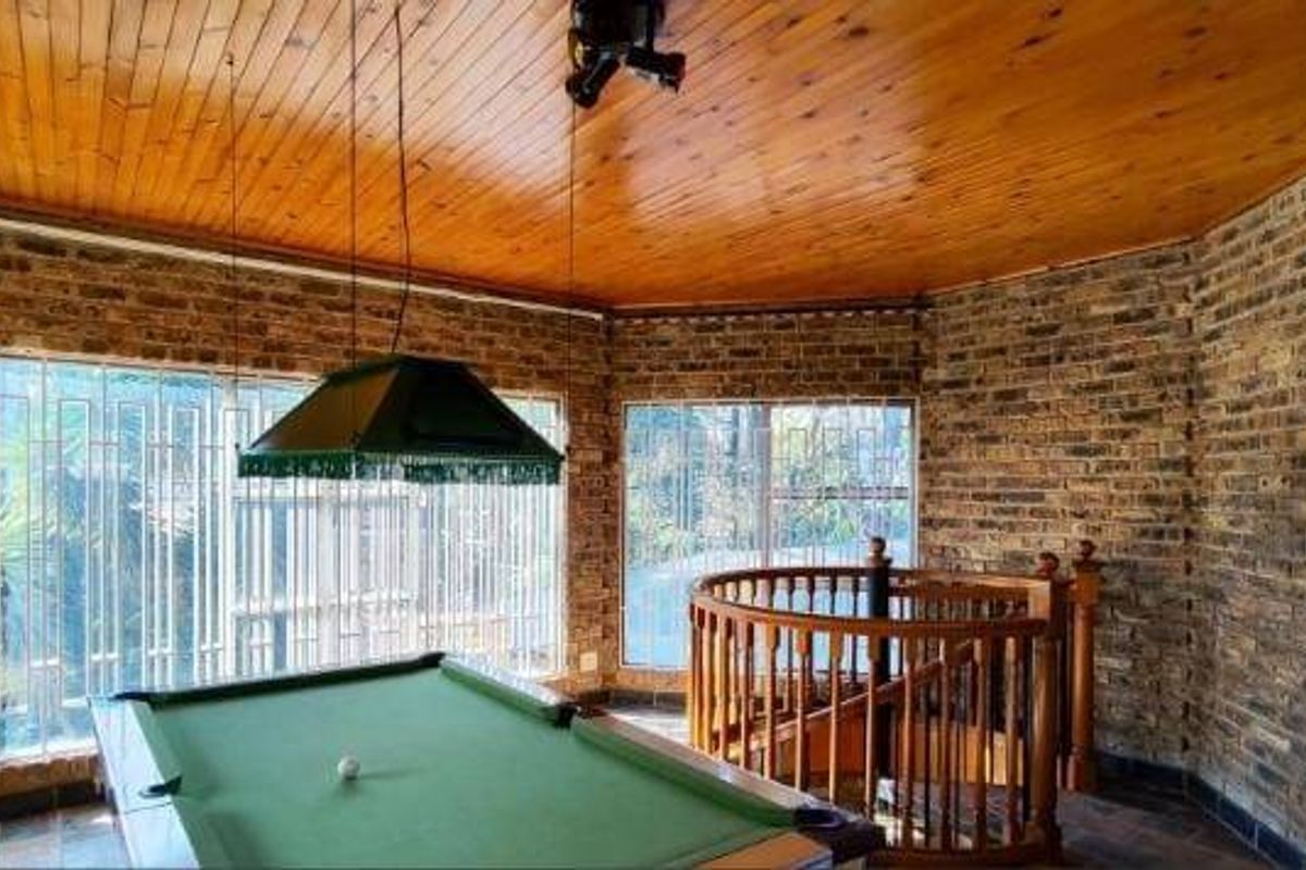Spacious living area featuring exposed brick walls, a warm timber ceiling, and a spiral staircase leading to another level.