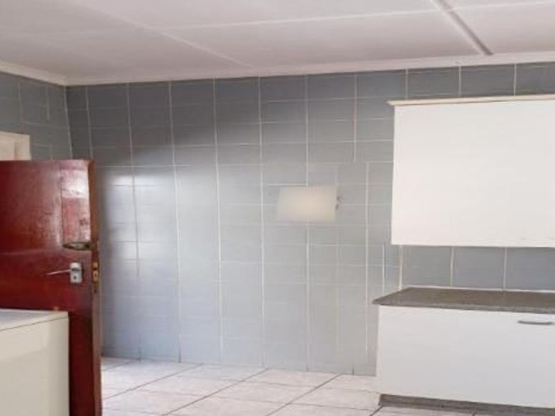A functional kitchen area featuring tiled walls, built-in cabinetry, and laminate countertops, offering a practical space ready for modernization.