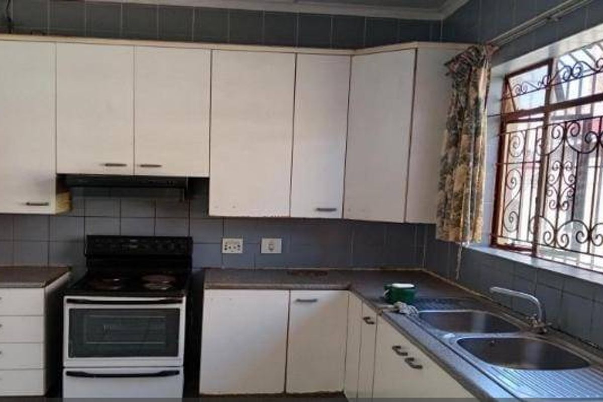 A functional kitchen featuring white built-in cabinetry, an electric stove with extractor fan, and a double basin sink with tiled backsplash.