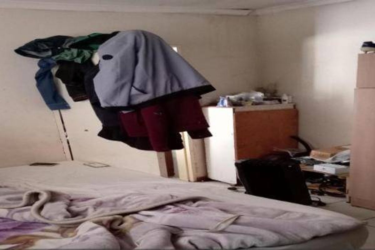 A bedroom featuring tiled flooring and a built-in wardrobe, currently showing signs of wear including peeling paint on the walls.