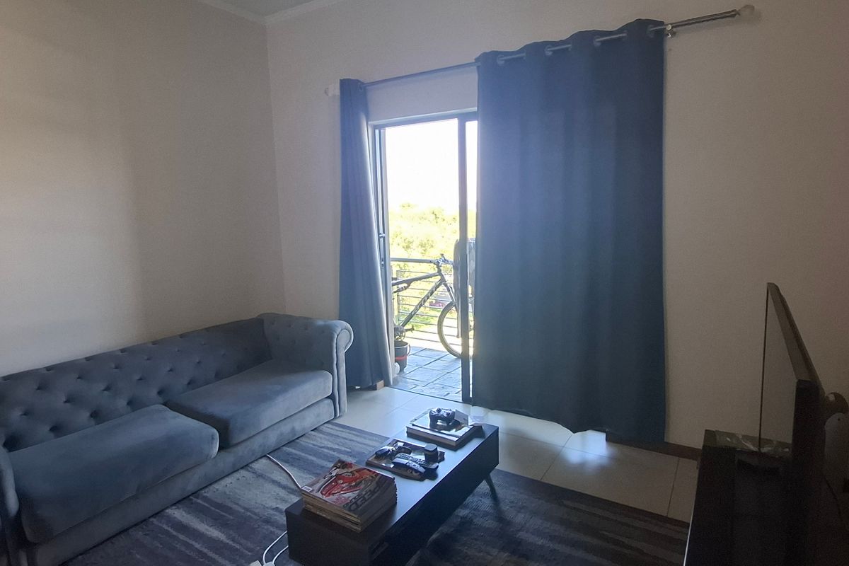 A living room featuring tiled flooring and a sliding glass door providing access to an outdoor balcony area.