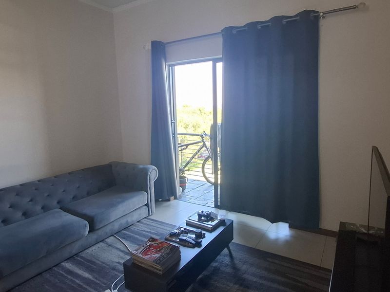 A living room featuring tiled flooring and a sliding glass door providing access to an outdoor balcony area.