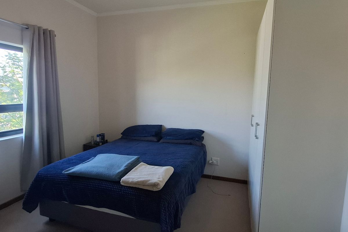 A functional bedroom featuring a built-in wardrobe and a window with natural light, providing a comfortable and practical living space.