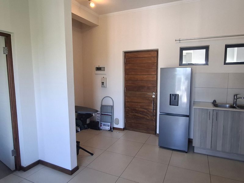 A functional kitchen area featuring built-in cabinetry, tiled flooring, and integrated appliances, with an open layout leading to adjacent living spaces.