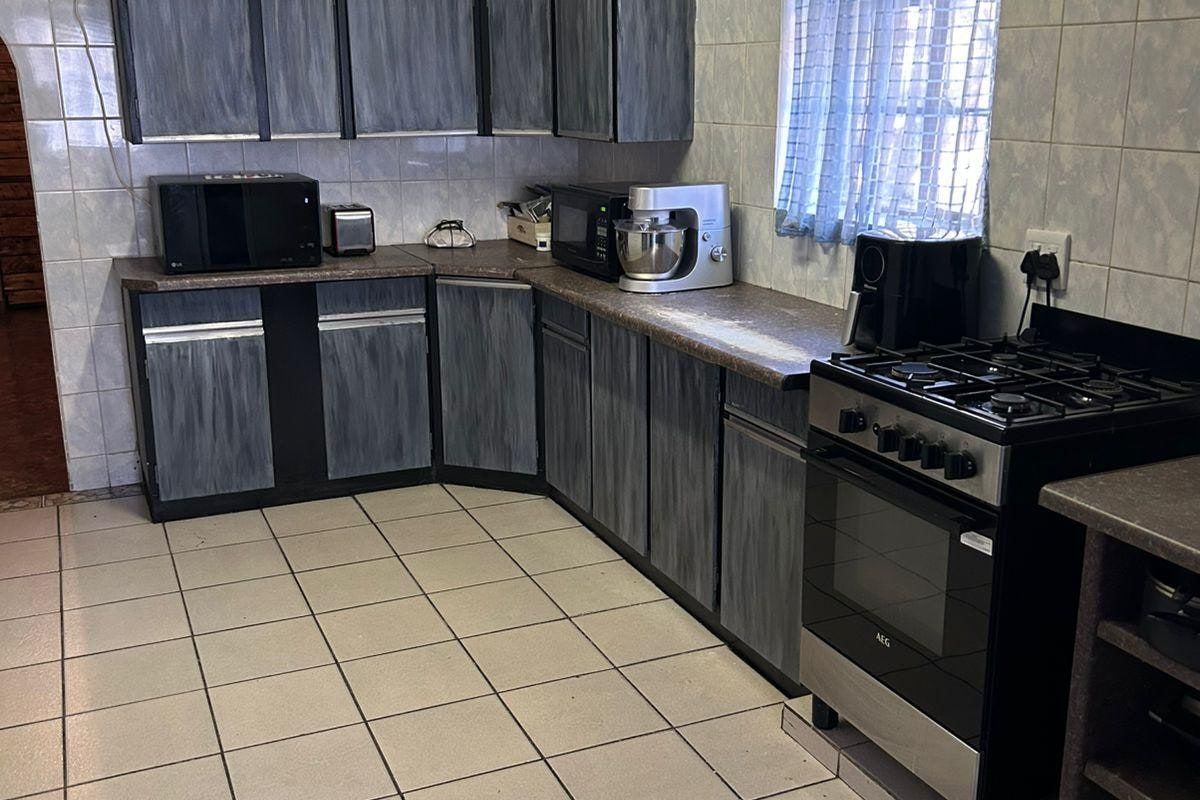 A functional kitchen featuring tiled flooring, wall-mounted air conditioning, and built-in cabinetry with a freestanding gas stove.