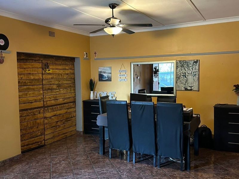Dining area featuring tiled flooring, a ceiling fan, and built-in wooden wall paneling, offering a functional space with potential for cosmetic updates.