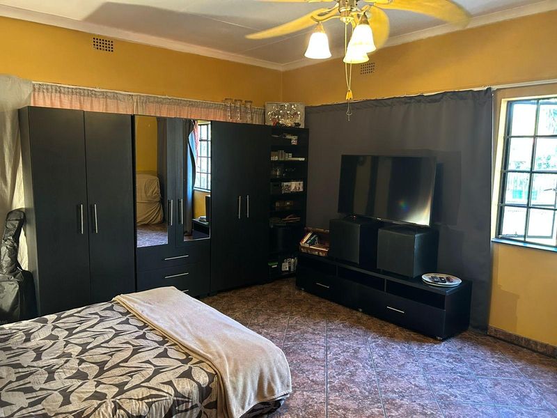 A bedroom featuring tiled flooring, a ceiling fan, and security burglar bars on the windows.
