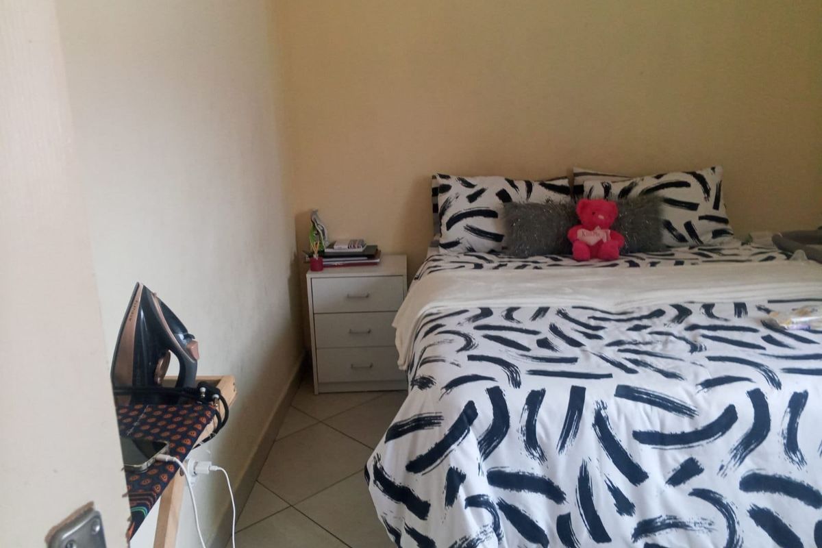 A standard bedroom featuring tiled flooring and neutral wall finishes, providing a functional space for rest.