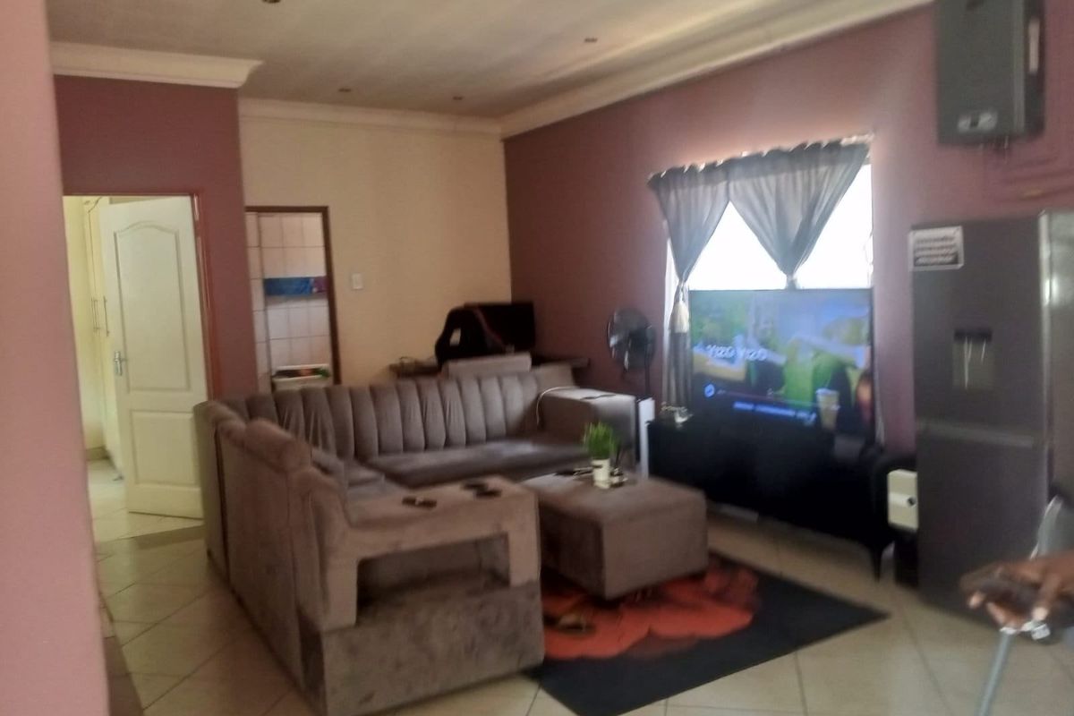 A living room featuring tiled flooring, recessed ceiling lighting, and coved cornicing, providing a functional space with direct access to adjacent rooms.