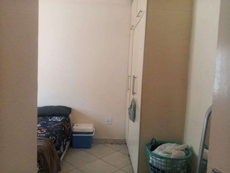 A functional bedroom featuring built-in cupboards and tiled flooring, offering a practical layout for a comfortable living space.