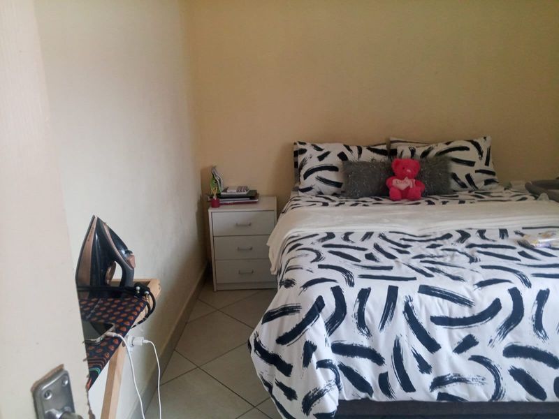 A standard bedroom featuring tiled flooring and neutral wall finishes, providing a functional space for rest.
