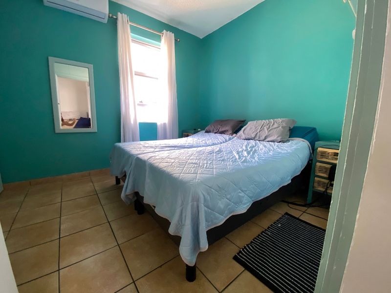 A bedroom featuring ceramic floor tiles and a wall-mounted split-system air conditioner.